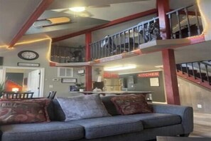 Ein mehrgeschossiges Wohnzimmer mit einer Couch, einem Esstisch und einer Küchenzeile.