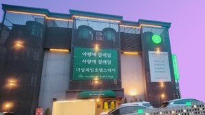 Un hotel de diseño moderno, con un llamativo letrero verde con texto en coreano, una tira de luz vertical y un logotipo circular verde.