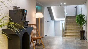 Un interior moderno con una cafetera, una lámpara, una silla y una escalera.