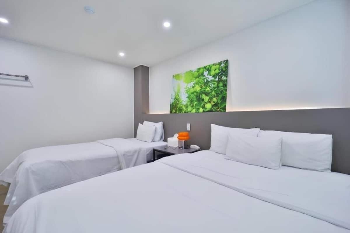 Habitación de hotel con dos camas, una mesita de noche, una lámpara y un cuadro colgado en la pared.
