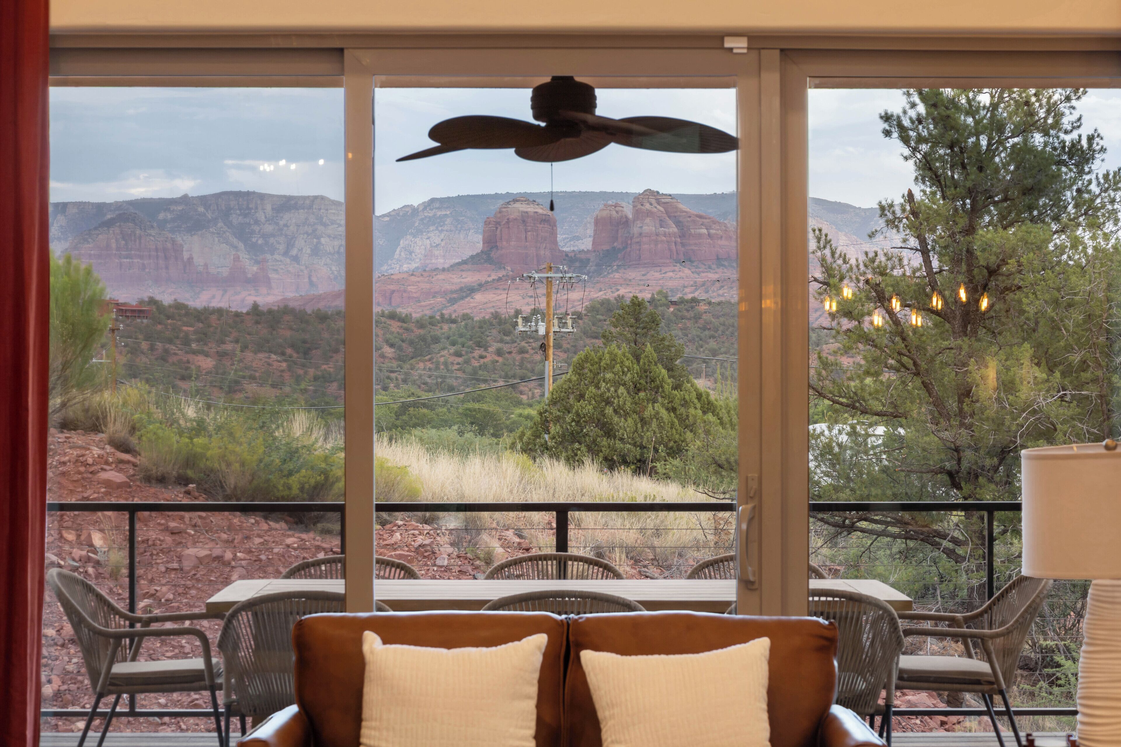 A room with a large window overlooking a mountainous landscape, furnished with a sofa and chairs.