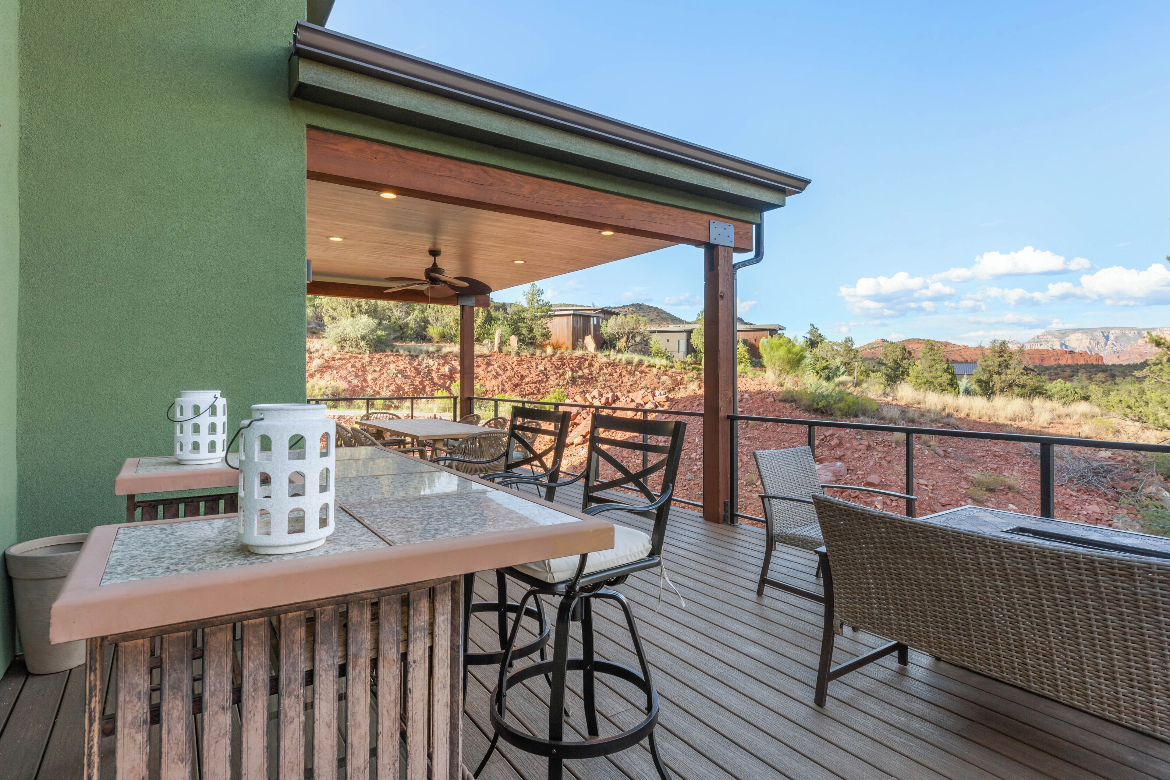 An outdoor patio with a wooden deck, a table with chairs, and a white lantern.