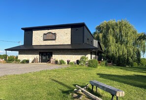 A two-story building with a stone facade, a large sign reading 'RR Ranch,' and a grassy area with a bench.