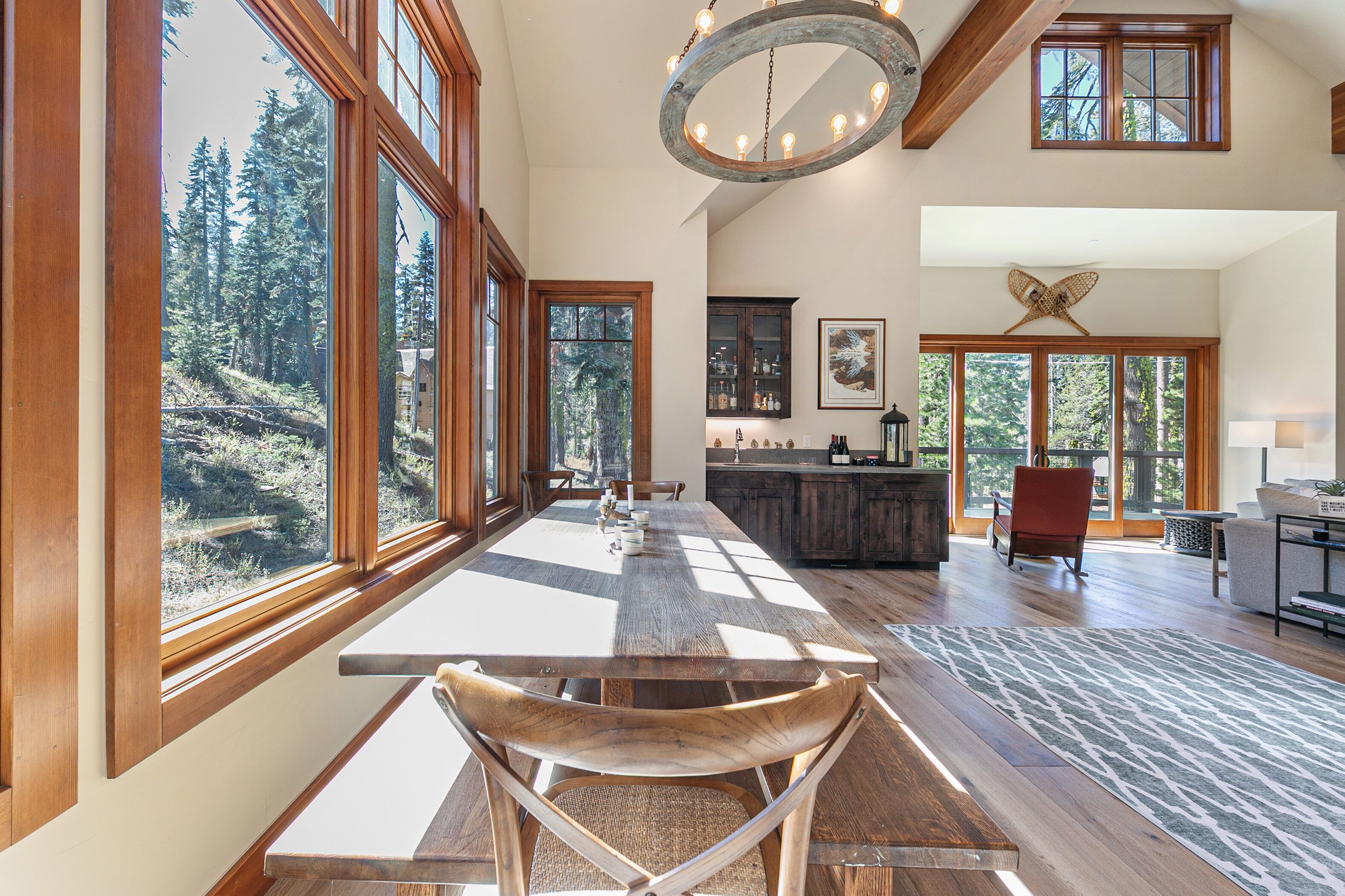 A spacious dining area with large windows, a wooden table, and chairs.