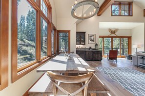 Un comedor amplio con ventanas grandes, una mesa de madera y sillas.