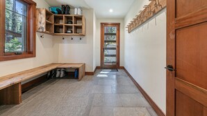 A hallway with a wooden bench, a shoe rack, and a door with a glass panel.