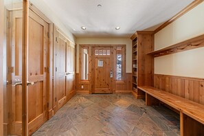 Un couloir avec des portes en bois, un banc et un sol carrelé.
