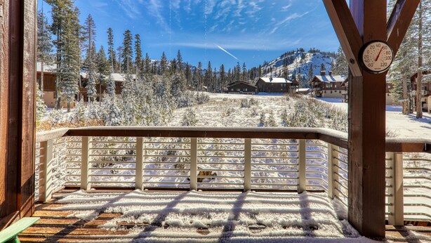 A wooden deck with a snow-covered landscape and a clear sky.
