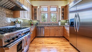 A kitchen with wooden cabinets, a stainless steel refrigerator, a dishwasher, and a granite countertop.