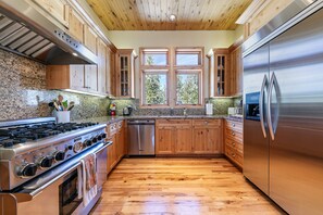 A kitchen with wooden cabinets, a stainless steel refrigerator, a dishwasher, and a granite countertop.