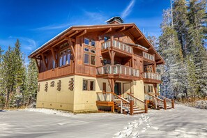 Una cabana de fusta de diversos pisos amb balcons, una escala i un paisatge cobert de neu.