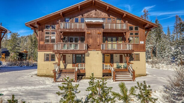 Eine zweistöckige Holzlodge mit Balkonen, einer Veranda und einer Seilbahn im Hintergrund.