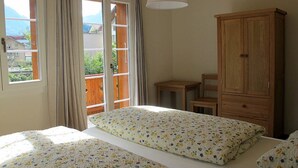 Een slaapkamer met een bed, een houten kast, een klein tafeltje en een stoel.