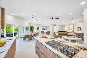 A modern kitchen with a central island, dining area with chairs, and a living room with a sofa and coffee table. - PRIVATE BEACH  / Heated Pool / Private Dock / Dolphin Key (Islamorada)