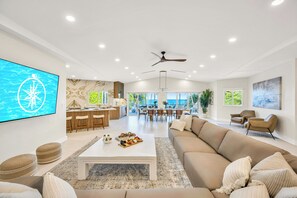 A spacious living area with a white coffee table, beige sofa, and a TV mounted on the wall.