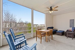 Eine überdachte Terrasse mit Esstisch, Stühlen und Deckenventilator.