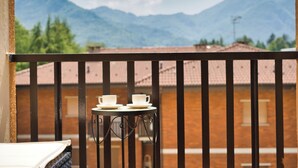 En balkon med et bord og to kopper, udsigt til et bjerglandskab.