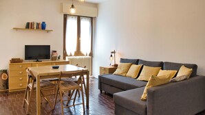 En moderne stue med sofa, spisebord, stole, fjernsyn og reol.