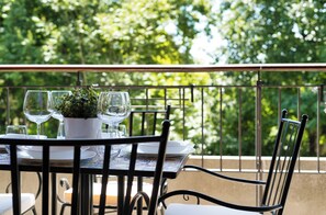 A table set outdoors with a potted plant, wine glasses, and a bowl. - Green Terrace Apartment in Lecco Center (Lecco)
