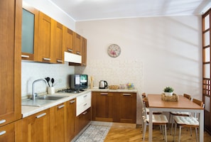Una cocina con armarios de madera, un fregadero, una estufa y un comedor con mesa y sillas.