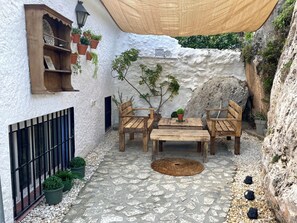 Um pátio com móveis de madeira, plantas em vasos e uma parede texturizada.
