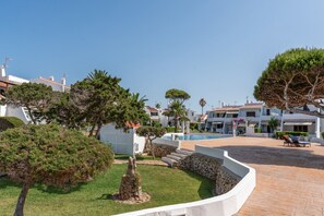 A courtyard with a swimming pool, stone walls, and a variety of trees.