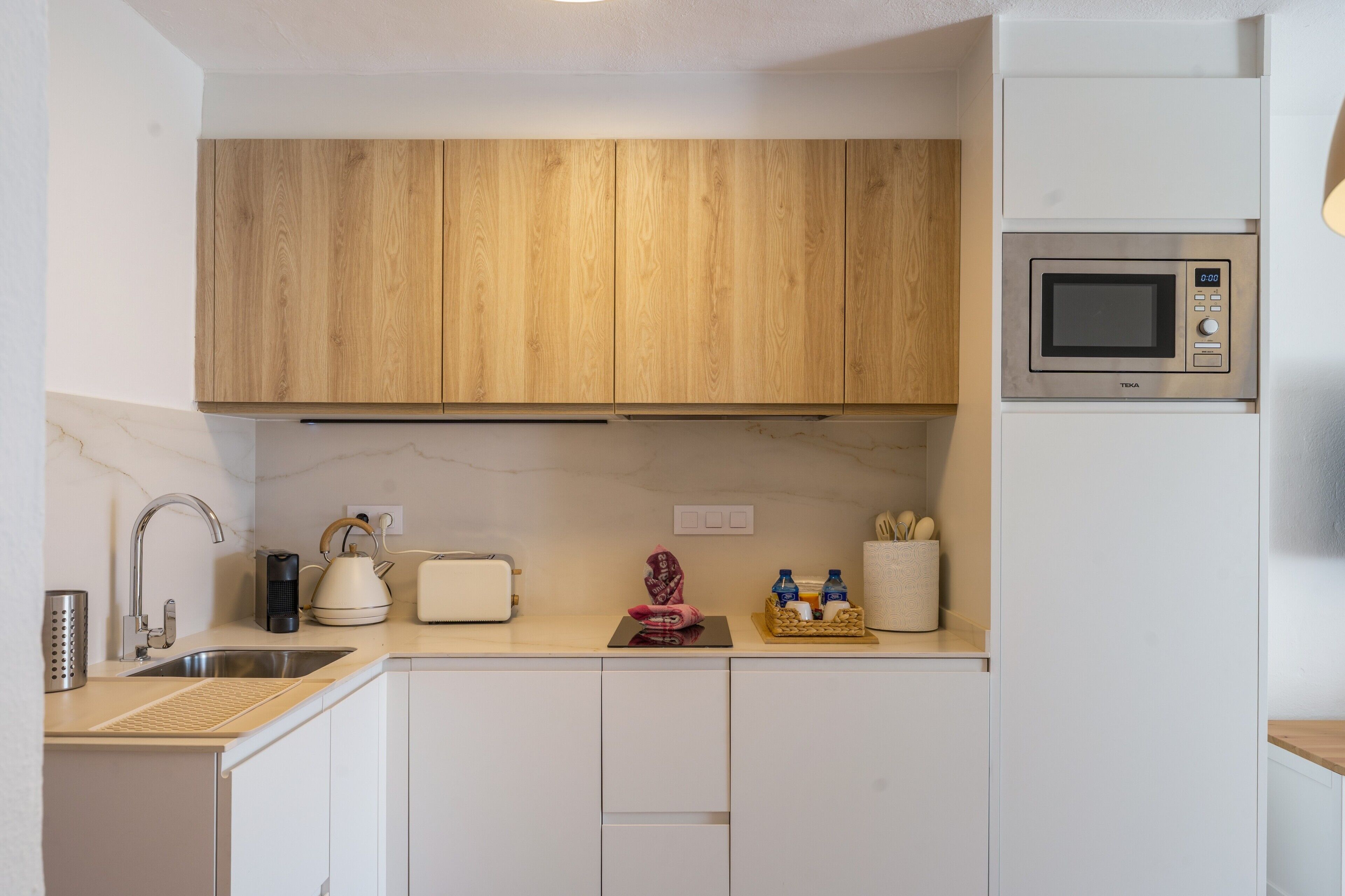 A modern kitchen with wooden cabinets, a microwave, a toaster, and a sink.