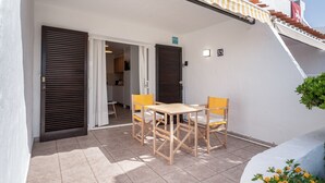 Un patio con mesa y sillas, un área cubierta y una escalera.