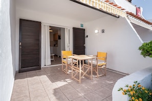 Une terrasse avec une table et des chaises, un espace couvert et un escalier.