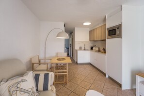 A compact living space with a kitchenette, a dining area with a table and chairs, and a sofa.