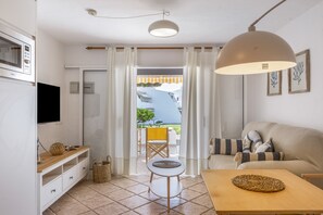 A modern kitchen with a microwave, a wooden table, a small round table, and a sofa.