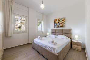 Ein Schlafzimmer mit einem großen Bett, zwei Nachttischen, einem Kopfteil und einem Bild an der Wand.