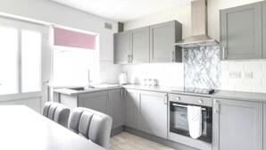 A modern kitchen with grey cabinets, a marble backsplash, and a built-in oven. - Bungalow - Sleeps 4 - Parking - Garden (Nottingham)
