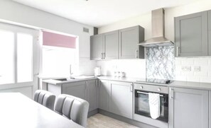 A modern kitchen with grey cabinets, a marble backsplash, and a built-in oven. - Bungalow - Sleeps 4 - Parking - Garden (Nottingham)