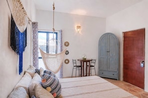 Ein Zimmer mit einem Bett, einem Hängesessel, einem Tisch mit Stühlen, einem Schrank und einer Tür.