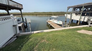 A dock with a boat, a covered area, and a grassy area. - Cozy Condo with Pool - Walk2Beach - Boat Slip - Sleeps 4 (Corpus Christi)