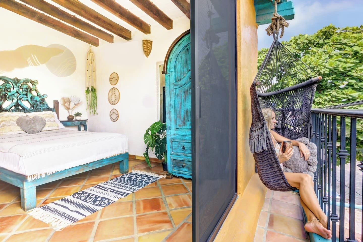 Un dormitorio con cama, una hamaca y vista a la vegetación.