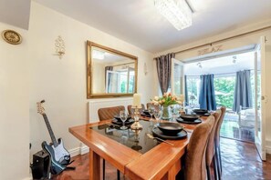 Un comedor con mesa de madera, sillas y una guitarra.
