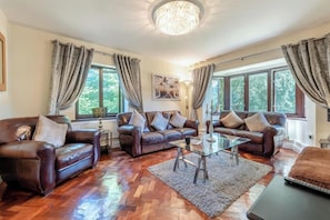 A spacious living room with leather sofas, a glass coffee table, and large windows with curtains. - Langlad Bay 2-Bed Apt, Sleeps 6 w/ Private Garden (Swansea)