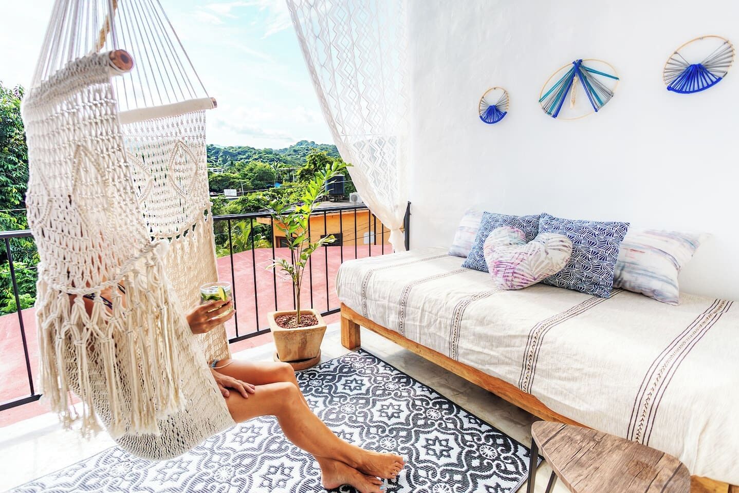 Un hamac sur un balcon, avec un lit et des objets décoratifs accrochés au mur.