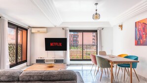 Un soggiorno moderno con un divano, un tavolo da pranzo con sedie, una televisione e un balcone con vista.
