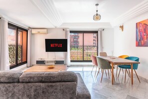 Ein modernes Wohnzimmer mit Sofa, Esstisch und Stühlen, Fernseher und einem Balkon mit Blick.