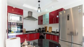 Una cucina moderna con mobili rossi, elettrodomestici in acciaio inossidabile e un'isola centrale.