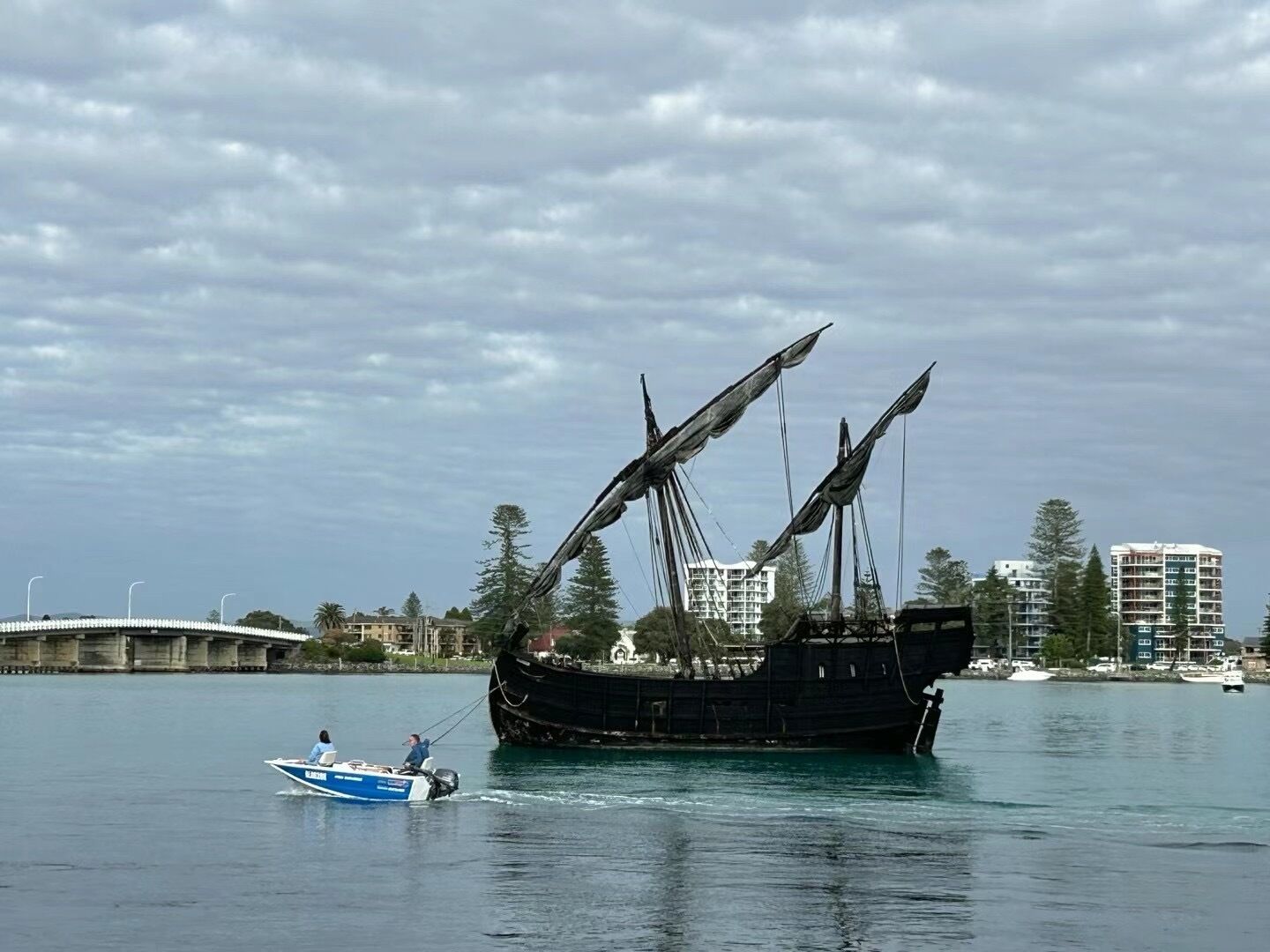 Un grand navire échoué dans des eaux calmes, avec un petit bateau à proximité.