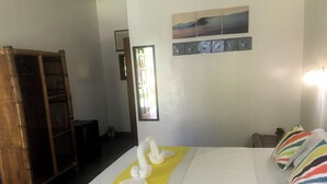 A hotel room with a bed, a wooden wardrobe, a window, and a wall-mounted artwork.