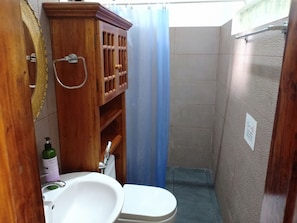 Un baño pequeño con un mueble de madera, un lavabo blanco y un inodoro.