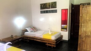 A room with a bed, a wooden wardrobe, a nightstand, and a wall-mounted lamp.