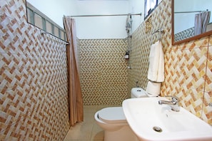 Un baño con baldosas estampadas, inodoro, lavabo y zona de ducha.