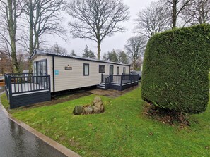 A mobile home with a fenced deck, a paved driveway, and a well-maintained lawn. - Cozy Retreat near Llanberis (Caernarfon)