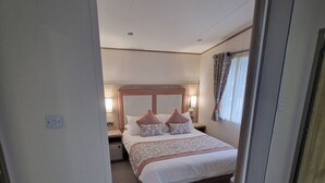 Una habitación de hotel con cama, mesitas de noche, armario y espejo.